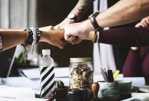 This is a photo of different arms and fists meeting in the center of the image for a team fist bump.