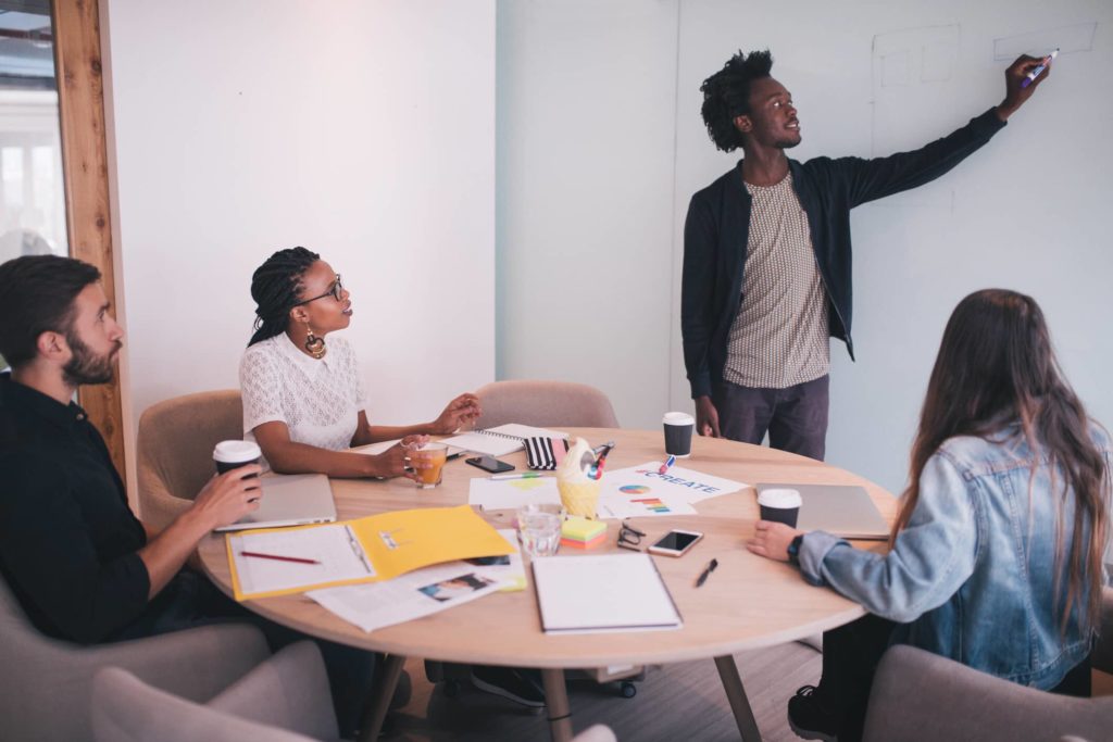 This is a photograph of a group of professionals in a conference room who are brainstorming on a white board to exemplify the act of creating a website strategy.