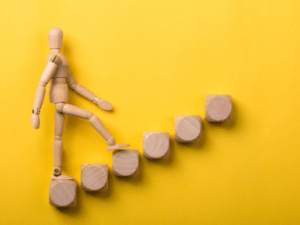 This is a photo of a jointed wooden mannequin walking up wooden steps.